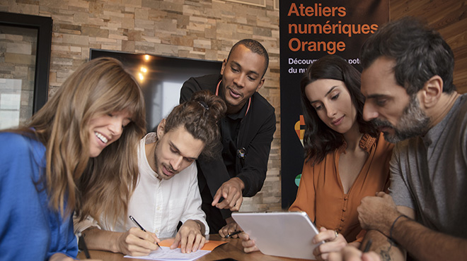 2 hommes et 2 femmes sont accompagnés d'un ambassadeur Orange lors d'un atelier numérique