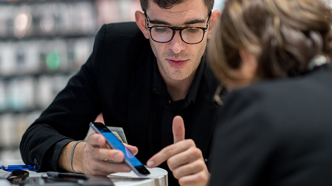 un conseiller en boutique Orange configure le smartphone d'une cliente