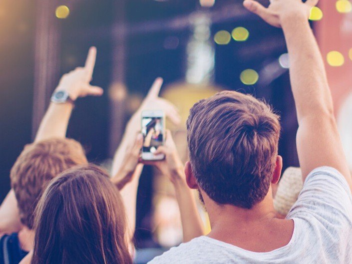 Photo de jeunes utilisant leur téléphone à un concerte de musique