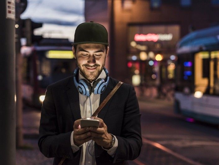 Photo d'un homme utilisant son mobile à proximité des transports en commun