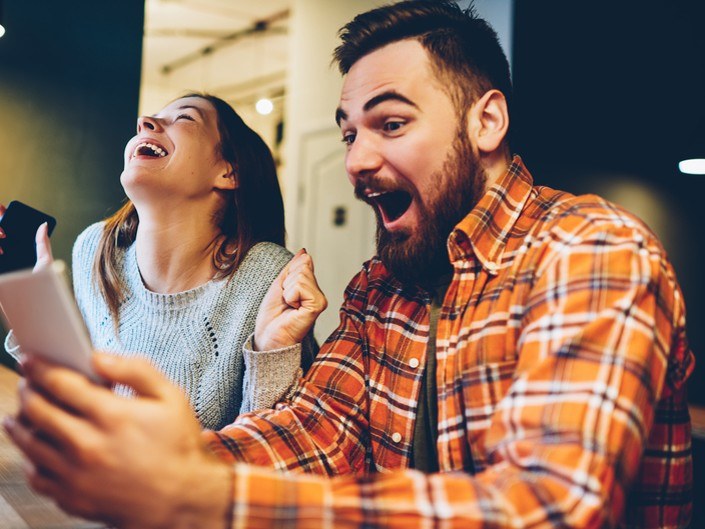 Photo d'un couple à domicile utillisation avec bonheur leur téléphone mobile