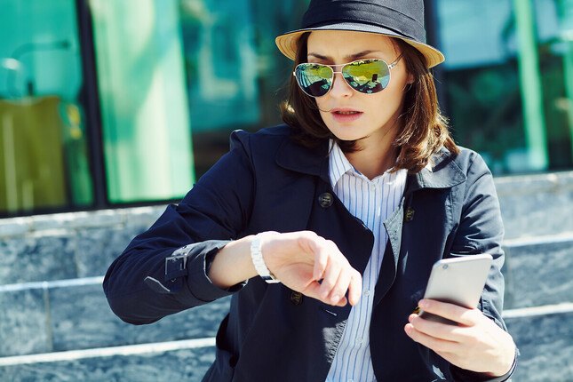 Photo d'une femme regardant sa montre connectée et tenant un téléphone mobile