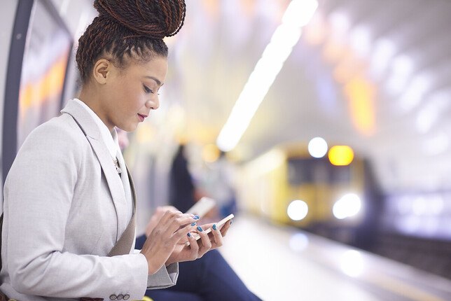 Photo d'une femme utilisant son téléphone portable sur le quai d'un métro