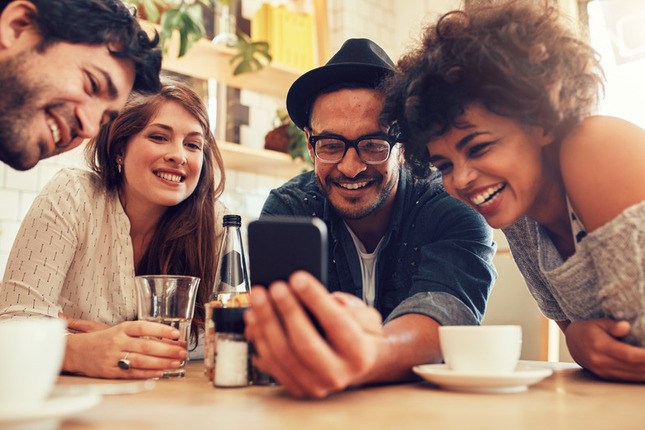 Photo au restaurant d'un homme montrant son téléphone à ses amis