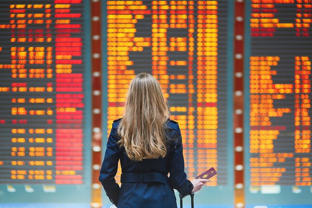 Photo d'une femme devant l'écran des départs à l'aéroport