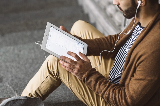 Photo d'un homme utilisant sa tablette avec un casque audio filaire