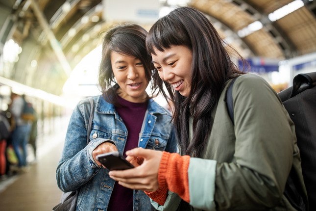 Photo de 2 touristes utilisant leur téléphone dans une gare ferroviaire