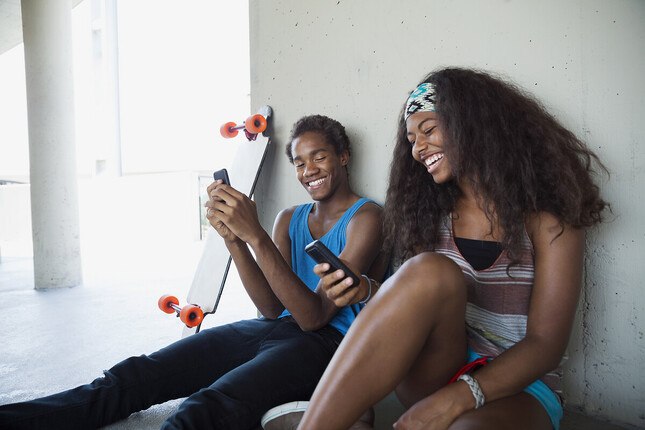 Photo de 2 jeunes se montrant leur écran de téléphone mobile