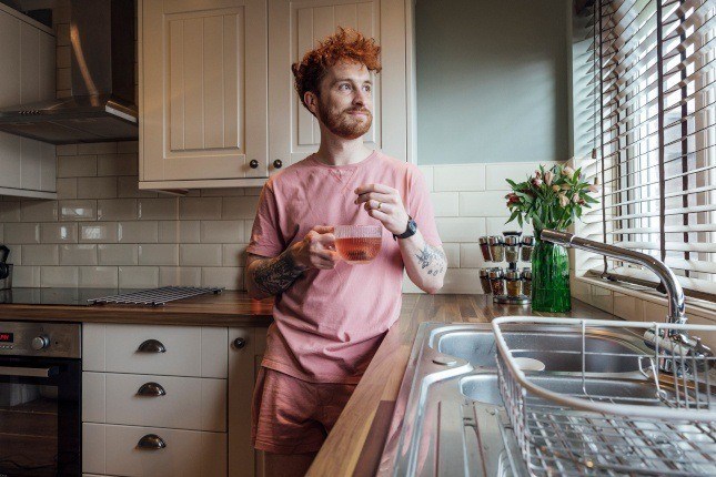 Photo d'un homme dans sa cuisine avec stores aux fenêtres