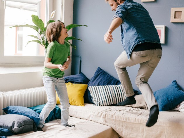 Photo d'un père et son fils sautant sur le canapé