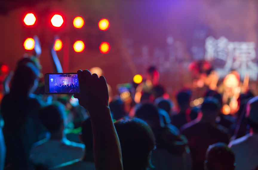 Photo d'un spectateur filmant un concert avec son téléphone